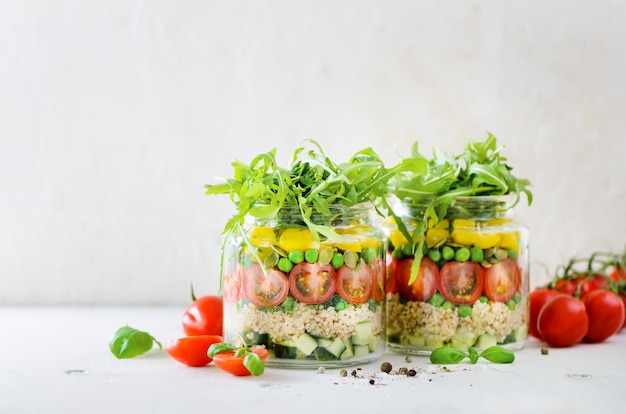 Frasco saudável da salada com quinoa e vegetais, tomates de cereja, pepino, ruccola. Refeição vegetariana crua para dieta, desintoxicação, comer limpo.