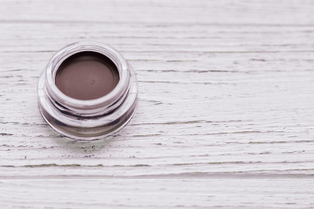 Un frasco con sombra de ojos y pomada para cejas sobre un fondo blanco.