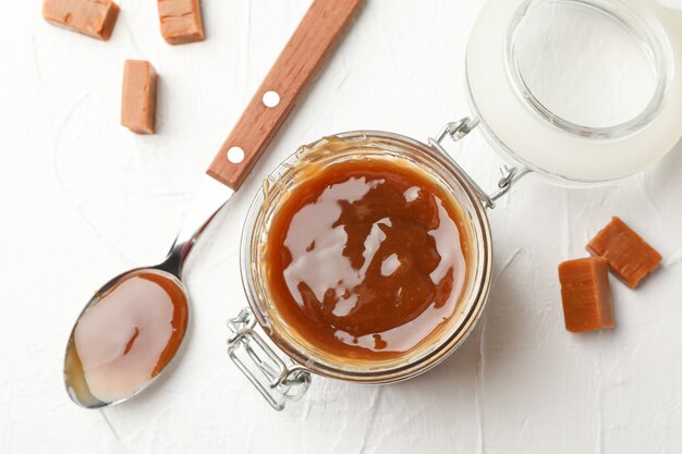 Frasco de vidrio con caramelo salado y dulces en el espacio en blanco, vista superior