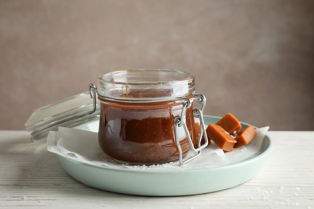 Frasco de vidrio con caramelo salado y dulces en espacio de madera, espacio para texto