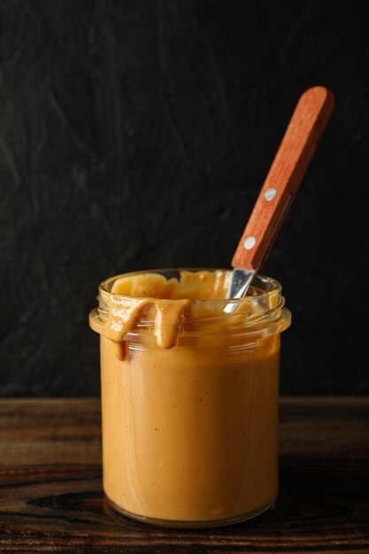 Frasco de vidrio con mantequilla de maní y una cuchara en la mesa de madera