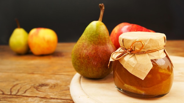 Frasco de vidrio de mermelada casera de pera y manzana con frutas frescas en la mesa