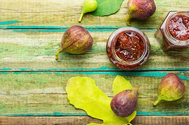 Frasco de vidrio con mermelada de higos sobre mesa de madera rústica