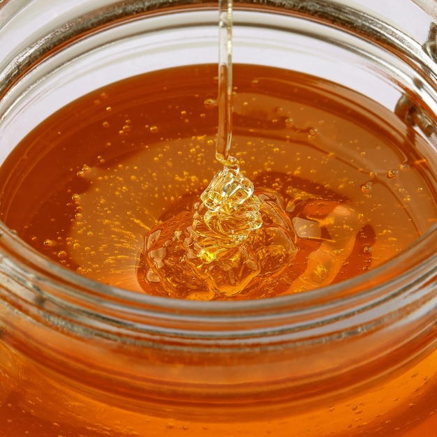 Foto frasco de vidrio con miel aislado sobre un fondo blanco.