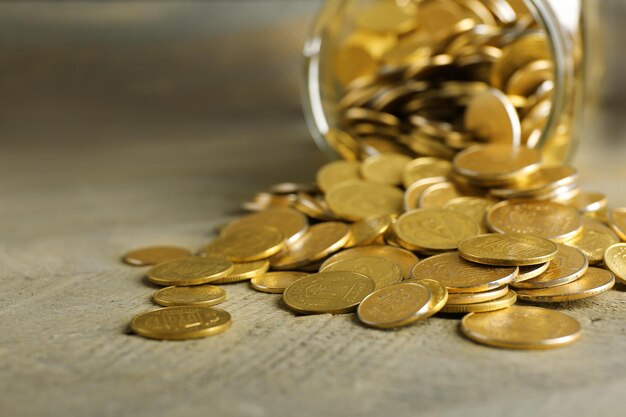 Frasco de vidrio con monedas sobre fondo de madera