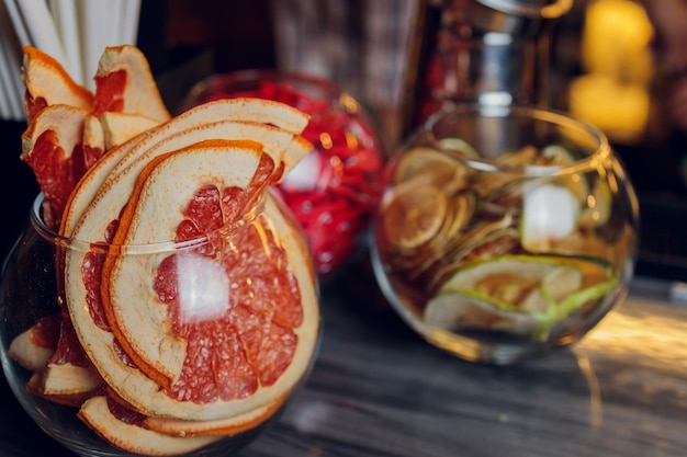 Frasco de vidrio con rodajas de cítricos de pomelo rojo seco en la mesa Fondo gris con espacio de copia