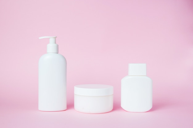 Foto frascos brancos de cosméticos em rosa