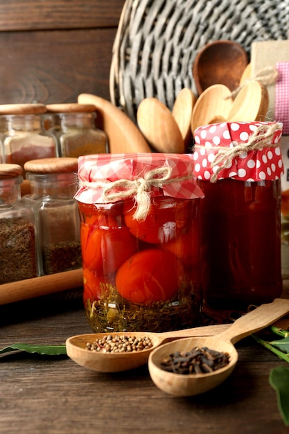 Frascos com especiarias de feijão de legumes em conserva e utensílios de cozinha em fundo de madeira