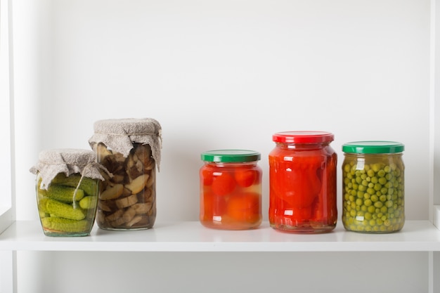 Foto frascos com legumes em conserva na mesa branca