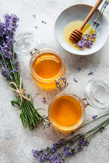 Frascos com mel e flores frescas de lavanda em um fundo de concreto