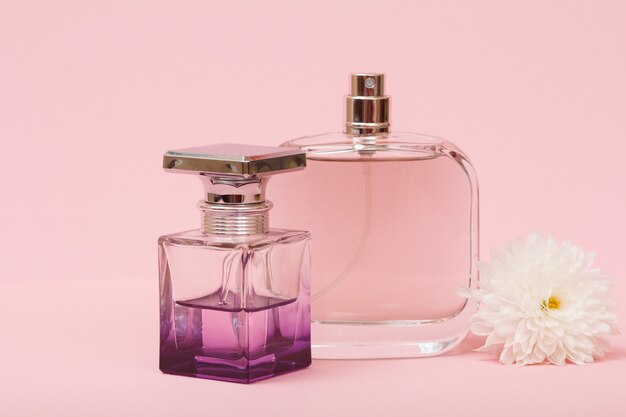 Frascos com perfumes femininos e botão de flor em um fundo rosa. produtos femininos.