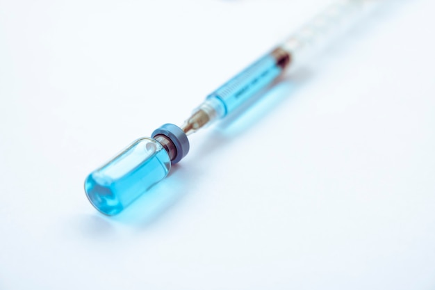 Frascos de closeup com vacina e seringa para proteção contra vírus isolados no fundo branco
