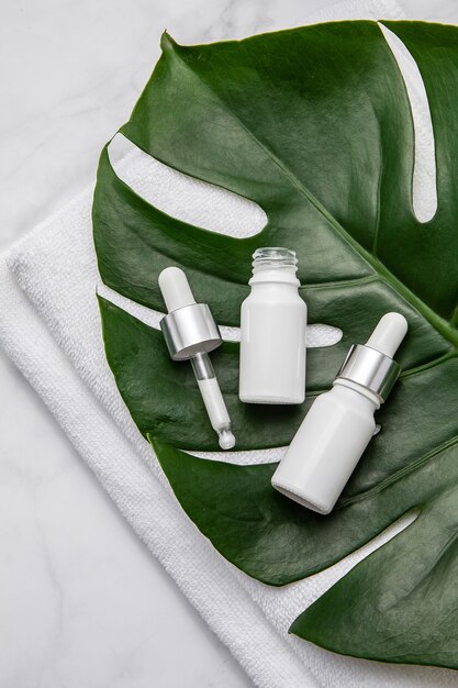 Frascos de cosméticos brancos com folhas verdes em branco