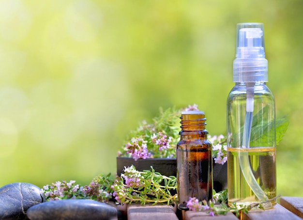 Frascos de óleo essencial e flores de ervas aromáticas sobre uma mesa e sobre fundo verde