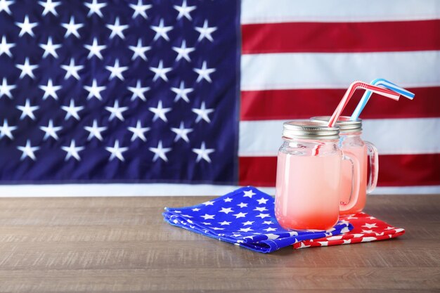 Frascos de pedreiro com coquetel alcoólico na mesa contra o fundo da bandeira americana