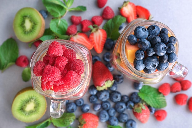 Frascos de pedreiro com frutas e bagas na mesa