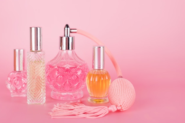 Foto frascos de perfume transparente diferente no fundo rosa