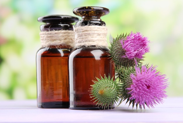 Frascos de remédios com flores de cardo no fundo da natureza