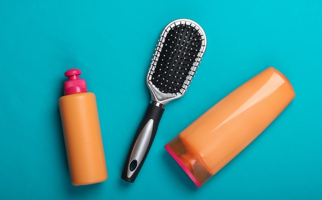 Frascos de shampoo, condicionador de cabelo, escovas de cabelo em azul. Cuidado capilar. Higiene