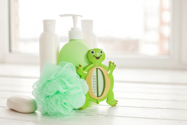 Frascos de shampoo na mesa de madeira. Acessórios de banho para bebês. Material de banheiro infantil. Tubos de banheiro, bálsamo, sal marinho, sabão.