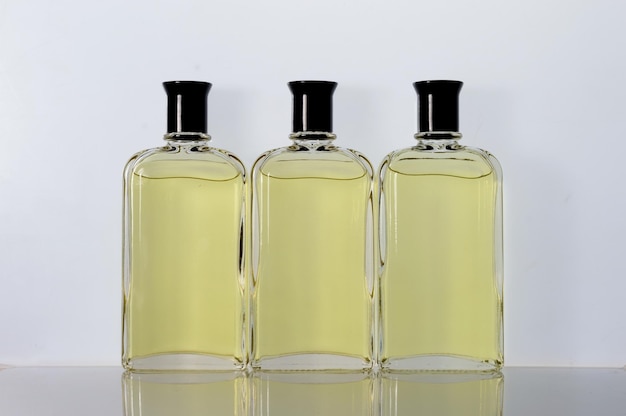 Frascos de vidro transparente com líquido de perfume sobre uma superfície branca