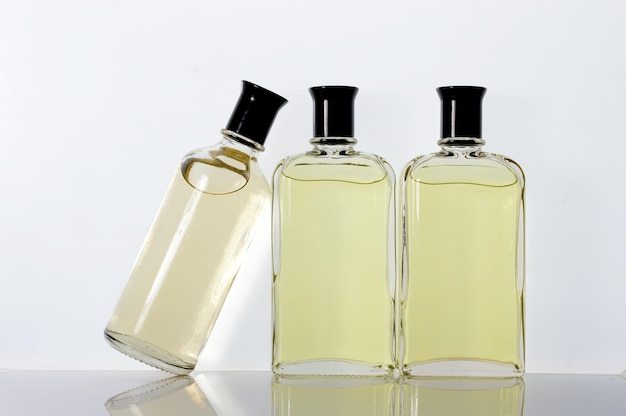 Frascos de vidro transparente com líquido de perfume sobre uma superfície branca