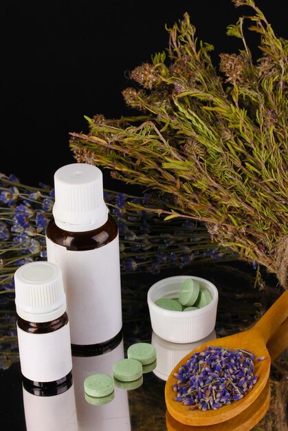 Foto frascos de medicamentos y hierbas sobre fondo negro concepto de homeopatía