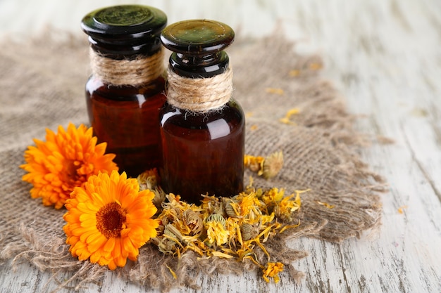 Frascos de medicina y flores de caléndula en mesa de madera