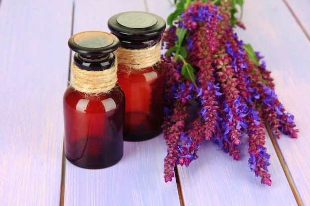 Frascos de medicina y flores de salvia en la pared de madera púrpura