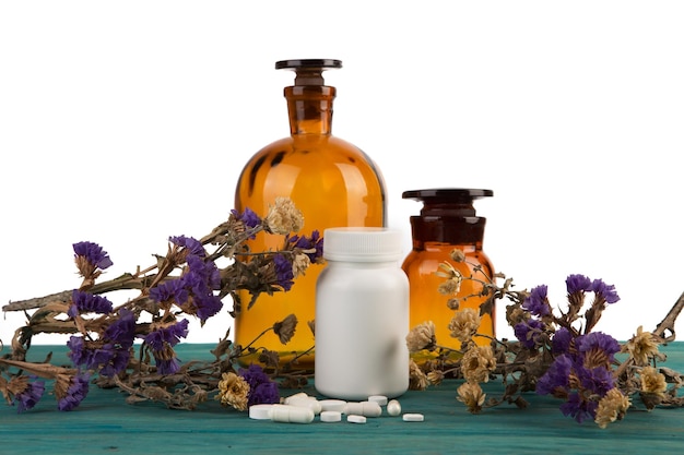 Foto frascos de medicina en mesa de madera aislado con flor y pils