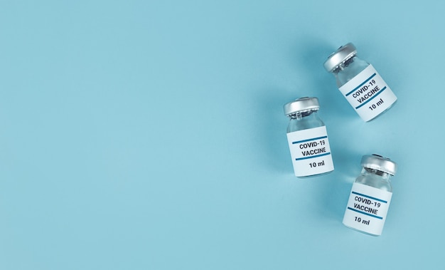 Frascos de medicina con vacuna covid 19 sobre fondo azul con espacio de copia.