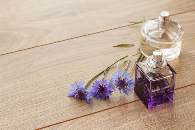 Frascos de perfumes con flores de mala hierba sobre tablas de madera