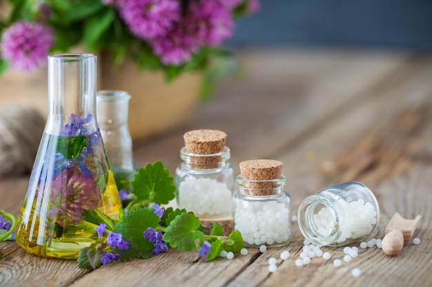 Frascos de tintura o infusión de hierbas saludables botellas de glóbulos de homeopatía y hierbas saludables en la mesa Concepto de medicina alternativa
