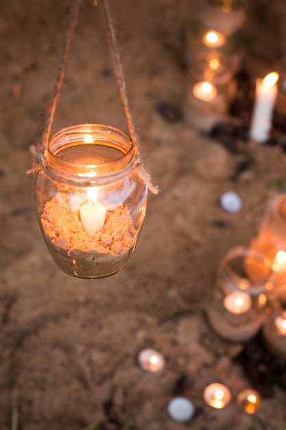 Frascos con velas y adornos de arena en la naturaleza.