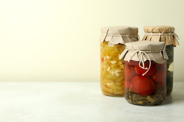 Frascos de verduras encurtidas sobre fondo blanco con textura