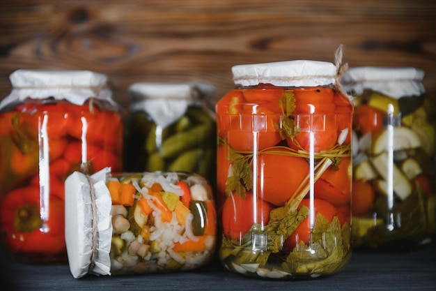 Frascos de verduras encurtidas sobre fondo de madera rústica