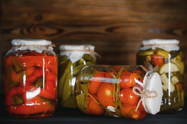 Frascos de verduras encurtidas sobre fondo de madera rústica