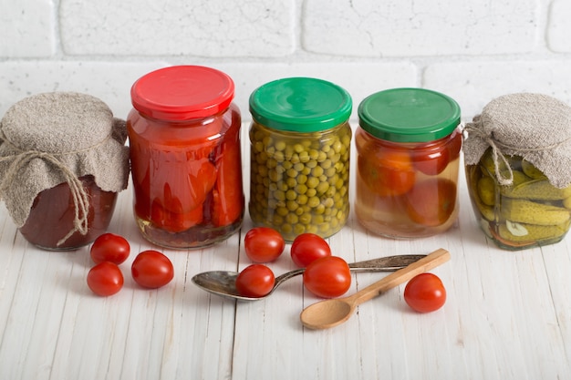 Frascos con verduras en escabeche en mesa blanca