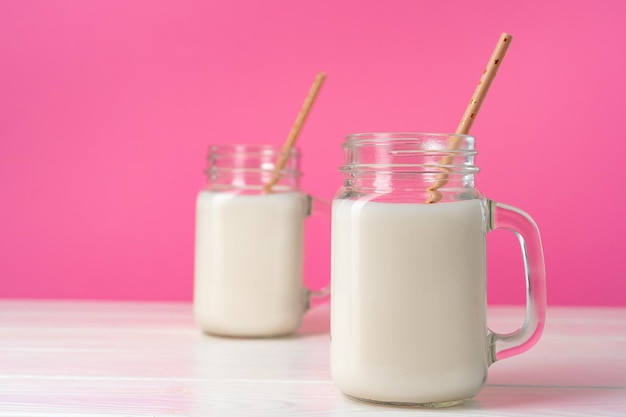 Frascos de vidrio con batidos aromatizados sobre fondo rosa