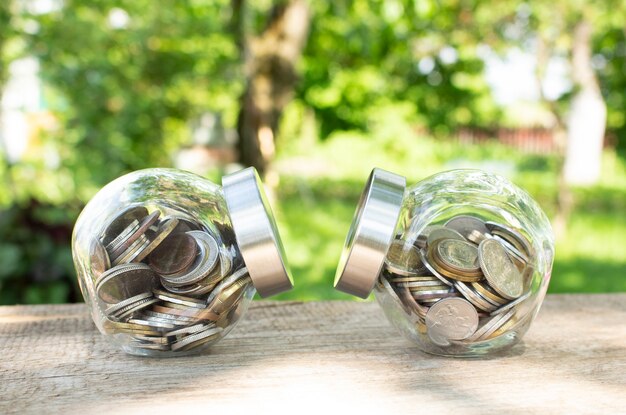 Frascos de vidrio con monedas sobre una mesa de madera. Presupuesto de inversión. Concepto financiero.