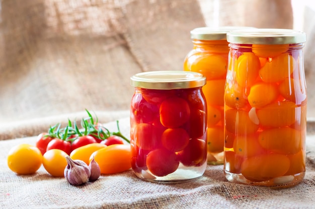 Frascos de vidrio con tomates en escabeche caseros, sellados con tapa de metal