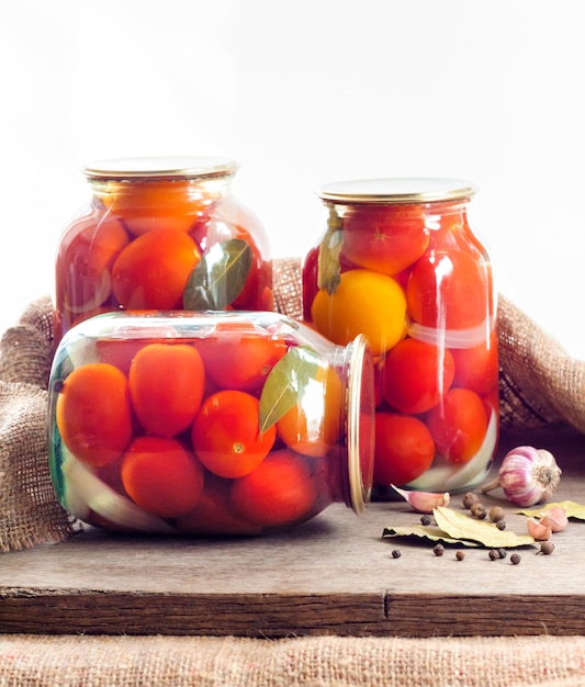 Frascos de vidrio con tomates rojos en escabeche, sellados con tapa de metal