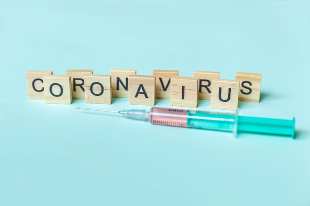 Frase de texto coronavirus e seringa na parede azul pastel. novo conceito de vacina contra o coronavírus 2019-ncov mers-cov covid-19 no oriente médio com a síndrome respiratória do vírus da coronavírus.