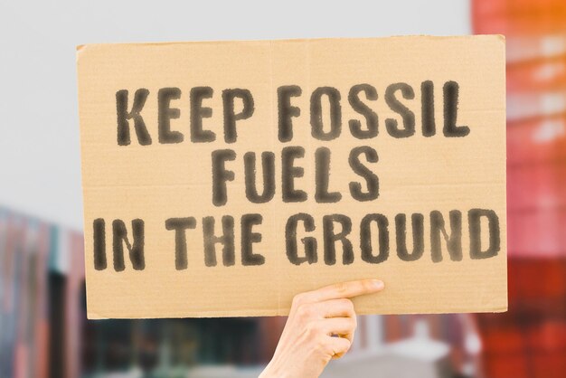 La frase Mantener los combustibles fósiles en el suelo en una pancarta en las manos de los hombres con un fondo borroso Carbono Gasolina Aceite Acción Combustible Energía Perforación Negar Negar Justicia Cambio Negativa Rechazar