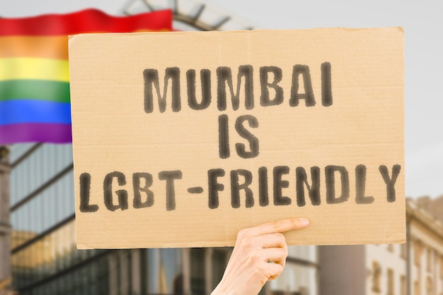 La frase Mumbai es LGBTFriendly en una pancarta en la mano de un hombre con una bandera LGBT borrosa