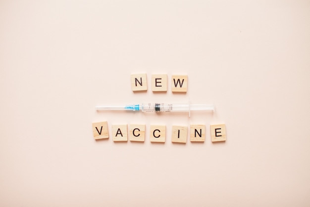 Frase nueva vacuna hecha de bloques de madera sobre un rosa claro