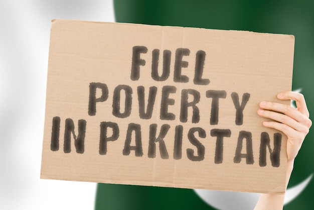 La frase "Pobreza de combustible en Pakistán" en una pancarta en la mano de los hombres con una bandera paquistaní borrosa en el fondo. Económico. Caro. Deprimido. Gasolina. Fósil. Problema. Suministro. Problemas sociales