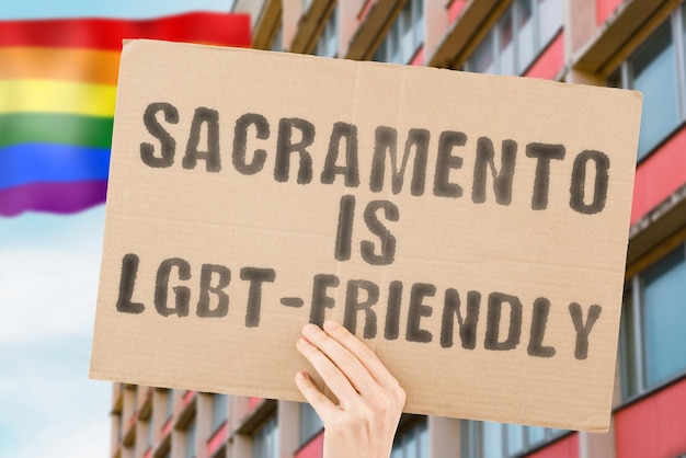 La frase "Sacramento es LGBT-Friendly" en una pancarta en la mano de los hombres con una bandera LGBT borrosa en el fondo. Relaciones humanas. diferente. Diverso. libertad. Sexualidad. Problemas sociales. Sociedad