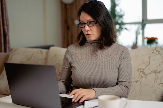 Frau 3040 Jahre alt mit Brille kommuniziert per Videokonferenz, die aus der Ferne arbeitet