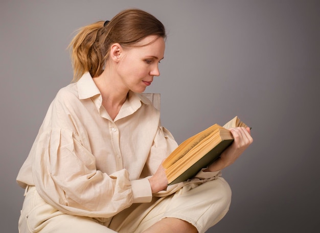 Frau 40 Jahre alt mit einem Buch auf hellem Hintergrund